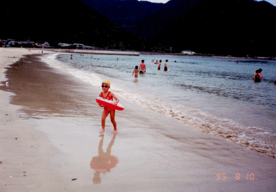 小学低学年、尾鷲の海で撮影した一枚。浮き輪を持って走る少女が、永岡さんご本人。