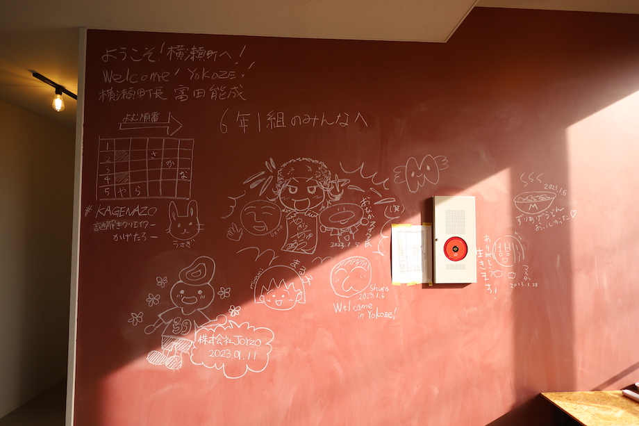 宿泊フロアの交流スペースにある黒板に、書き残されたメッセージやイラスト。富田町長のウェルカムメッセージも。