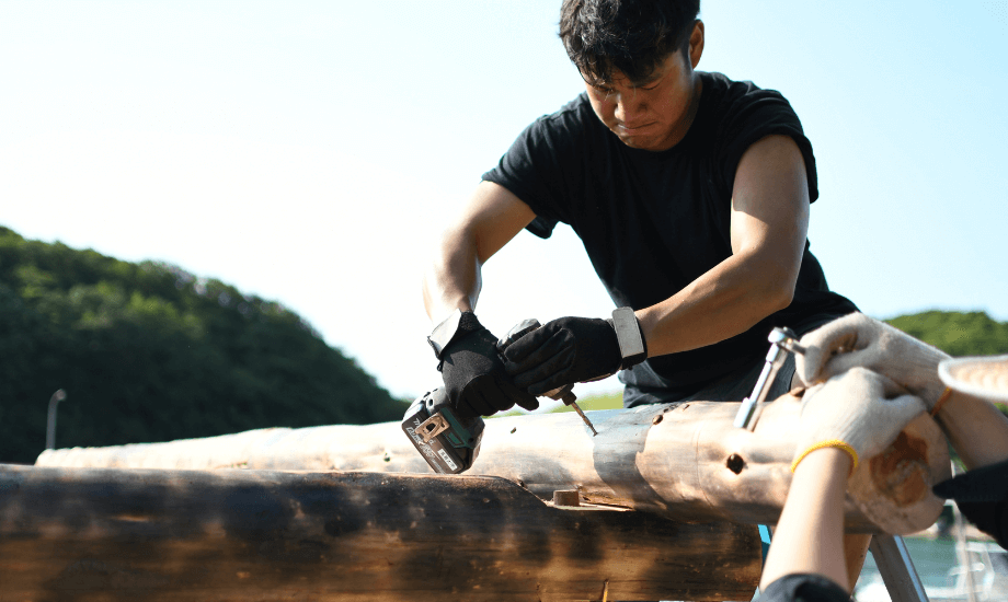 漁村の船小屋を改修するプロジェクトに参画する、大人の島留学生の様子。船小屋の屋根を修理している